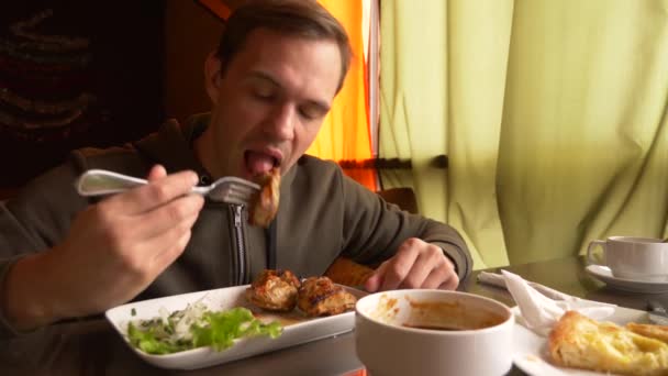 Человек в ресторане ест горячее мясо вилкой, 4К, замедленная съемка — стоковое видео