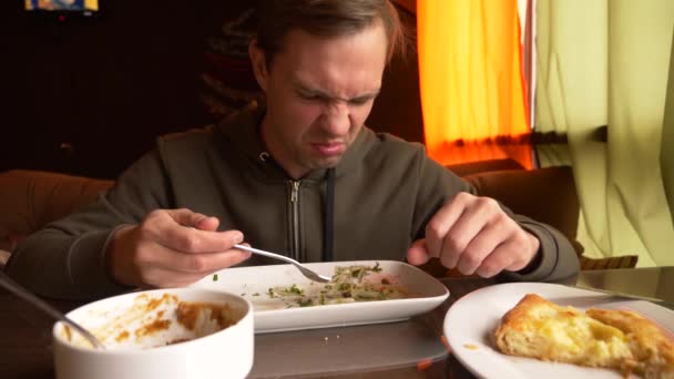 Hombre está comiendo en un café ensalada de verduras en un plato blanco. 4k, cámara lenta — Vídeos de Stock