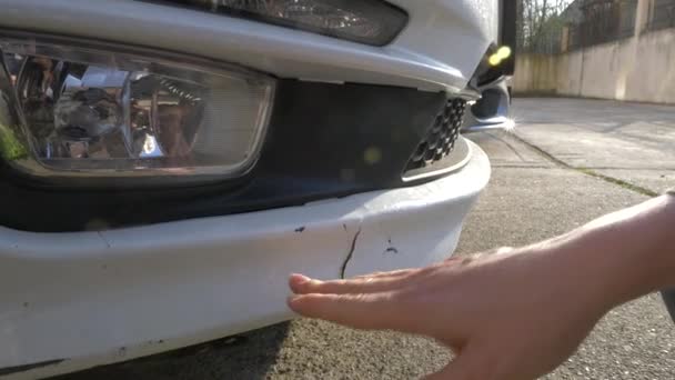 Mirando un vehículo dañado. Mujer rubia inspecciona daños en el coche después de un accidente — Vídeo de stock