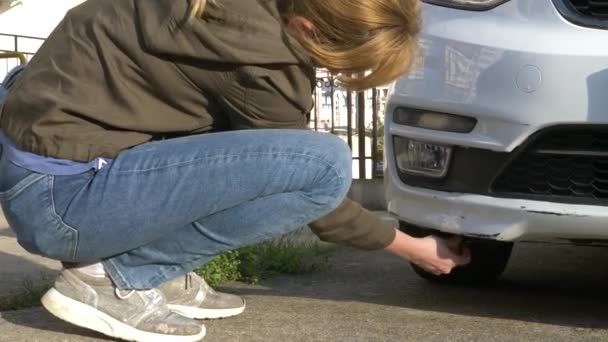 Blick auf ein beschädigtes Fahrzeug. Blondine inspiziert Autoschaden nach Unfall — Stockvideo