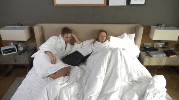 Jong koppel liggend in bed met behulp van laptopcomputer, online ... Jong koppel liggend in bed met behulp van laptopcomputer, online ...