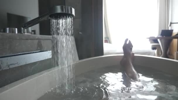 4k, mans jambes dans une salle de bain de l'hôtel. l'eau chaude se déverse dans le bain et de là vient la vapeur . — Video