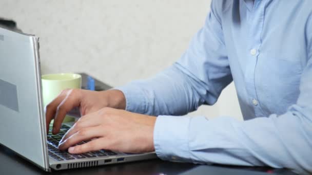 Молодой человек потягивает чай на ноутбуке во время работы в офисе. макро, 4k — стоковое видео