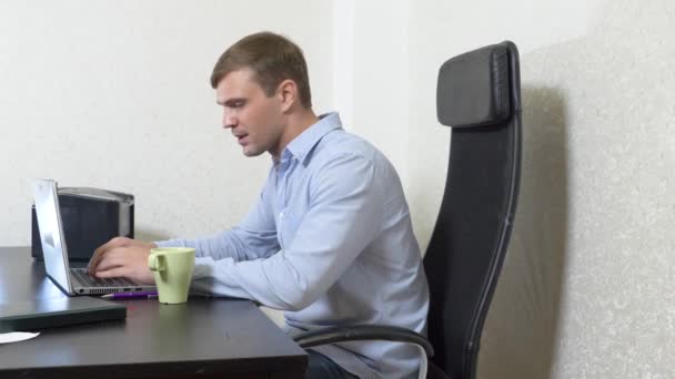 Young man sipping tea on laptop while working in office. Slow-motion shooting, 4k — Stock Video