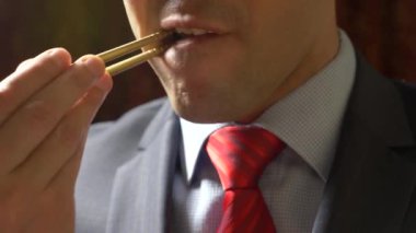 ceket ve kravat adam Doları rulo çubukla yemek. dolar ye. 4k.