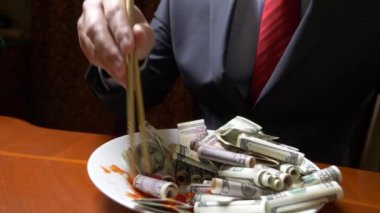 ceket ve kravat adam Doları rulo çubukla yemek. dolar ye. 4k.