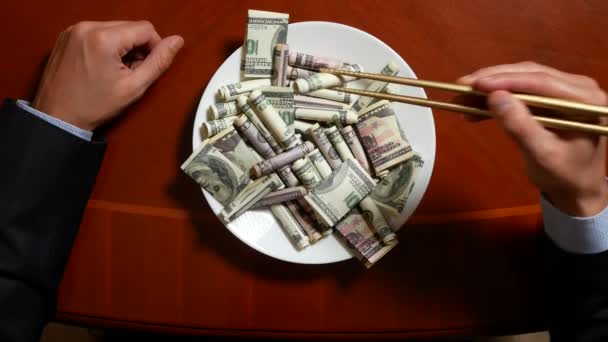 Hands of a businessman with chopsticks and dollar rolls. eating dollars. 4k. — Stock Video