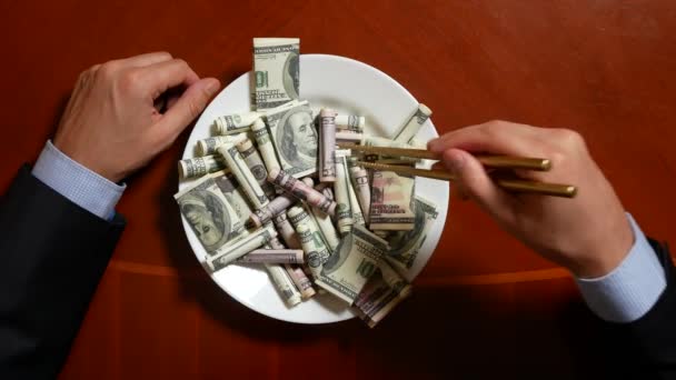 Mani di un uomo d'affari con bacchette e rotoli di dollari. mangiare dollari. 4k . — Video Stock