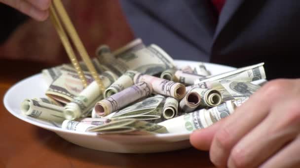 Mãos de um homem de negócios com pauzinhos e rolos de dólar. a comer dólares. 4k . — Vídeo de Stock