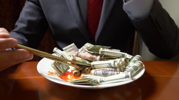 Ο άνθρωπος με το σακάκι και γραβάτα τρώει τα ρολά του δολαρίου με chopsticks. φάτε δολάρια. 4k. — Αρχείο Βίντεο