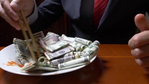 L'homme en veste et cravate mange les rouleaux du dollar avec des baguettes. manger des dollars. 4k . — Video