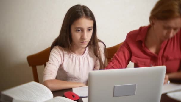 Mutter und Tochter arbeiten gemeinsam am Laptop an den Hausaufgaben. Online-Lernen, Online-Schule. 4k. — Stockvideo