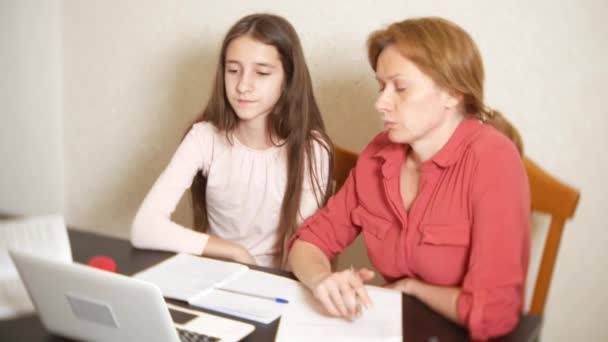 Madre e hija trabajando juntas en una tarea en un portátil. aprendizaje en línea, escuela en línea. 4k . — Vídeo de stock