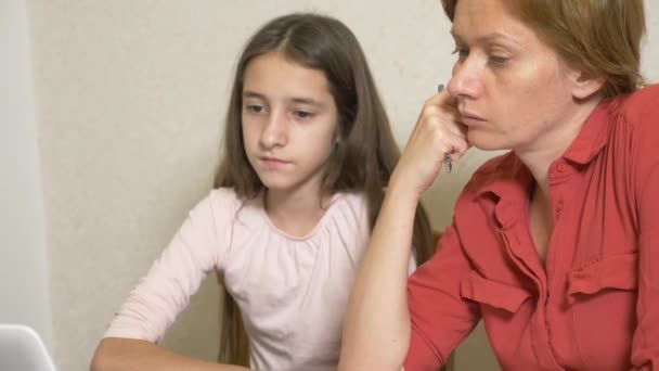 Madre e hija trabajando juntas en una tarea en un portátil. aprendizaje en línea, escuela en línea. 4k . — Vídeos de Stock