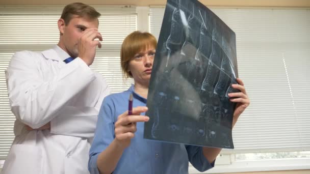 Intimidatie in het ziekenhuis. de dokter vraagt zijn collega tijdens de analyse van de resultaten van magnetisch-resonantie therapie. 4k, slow-motion — Stockvideo