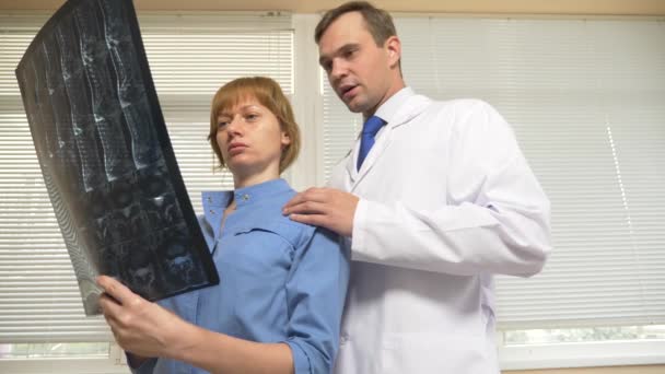 Trakasserier på sjukhuset. Läkaren ber hans kollega under analysen av resultaten av magnetiska-resonans terapi. 4k, Slowmotion — Stockvideo