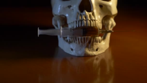 Crânio e seringa de líquido amarelado. drogas conceituais. 4k, atirar boneca — Vídeo de Stock
