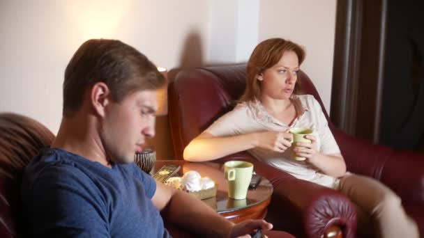 Pareja feliz marido y mujer están sentados en casa en la sala de estar, hablando relajarse y beber té tarde en la noche. 4k — Vídeos de Stock