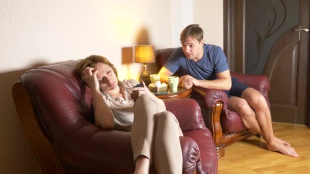 Noche familiar, marido y mujer se sientan en una silla en su casa y averiguar la relación. 4k — Vídeo de stock