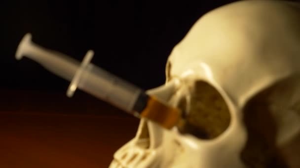 Crâne et seringue de liquide jaunâtre. concept drogues. 4k, tir de poupée — Video