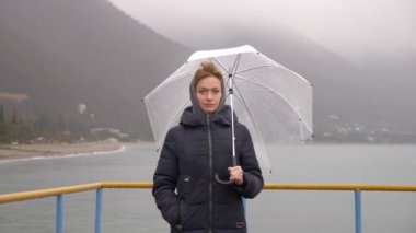 Yağmur altında bir yağmurlu, sonbahar gününde 4k denizden bir şemsiye altında bir kadın