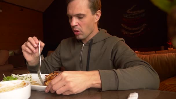 De man in het restaurant eet warm vlees met een vork, 4k, slow-motion-video schieten — Stockvideo