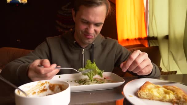 Мужчина ест в кафе овощной салат на белой тарелке. 4k, slow motion — стоковое видео