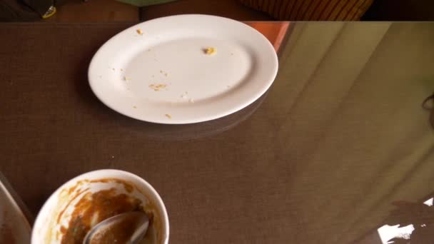 Empty dirty white plates with fork, spoon and waste food after eaten on table, 4k — Stock Video