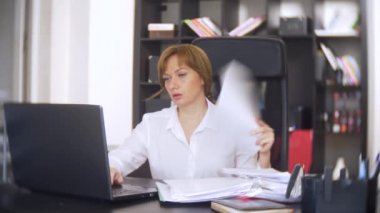 belgeler, inceden inceye gözden geçirmek bir işkadını frowns, bir dizüstü bilgisayar kullanarak, ofiste acil bir görev yapmaz, yeterli zaman değil 4k. ofis çok sıcak, Klima çalışmıyor