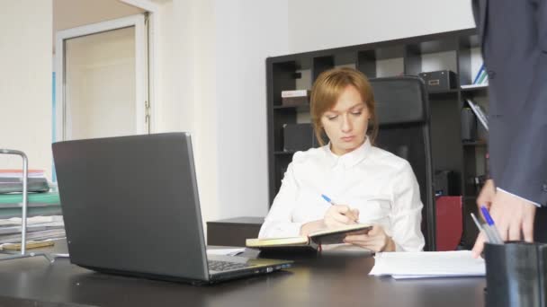 Man en vrouw in strikte pakken bij werken op de laptop, documenten, discussie in het kantoor. 4k. — Stockvideo