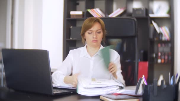 Affärskvinna som skannar dokument, rynkar pannan, använder en bärbar dator, utför inte en brådskande uppgift på kontoret, det finns inte tillräckligt med tid, 4k. — Stockvideo