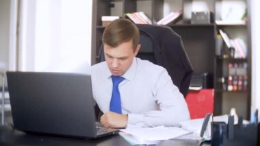 belgeler, inceden inceye gözden geçirmek bir işadamı, bir dizüstü bilgisayar kullanarak frowns, ofiste acil bir görev yapmaz, yeterli zaman değil 4k. ofis çok sıcak, Klima çalışmıyor