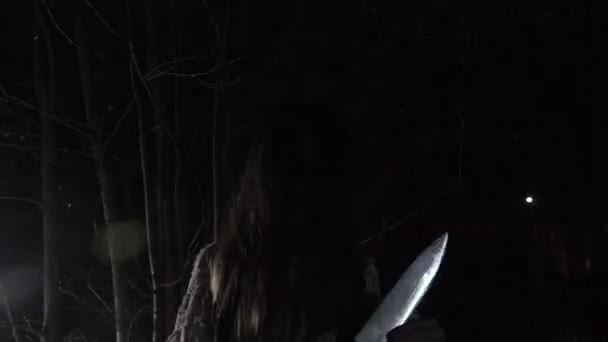 Una niña fantasma con el pelo largo y negro, en blanco, vagando por el bosque con un cuchillo y un juguete suave. 4k — Vídeos de Stock