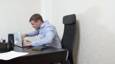 Genç bir adam çay bir dizüstü bilgisayar üzerine dökülür. ofiste çalışıyor. Ağır çekim silah, 4 k