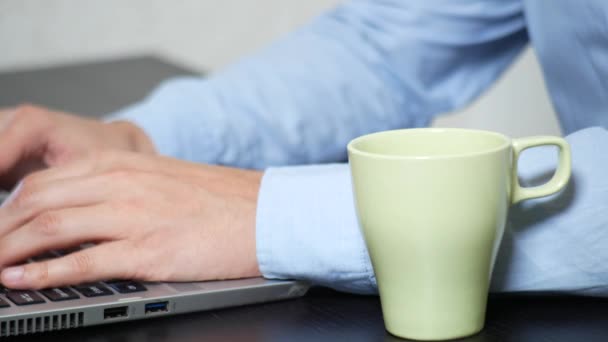Mladý muž naléval čaj na laptop. práce v kanceláři, 4 k detail, — Stock video