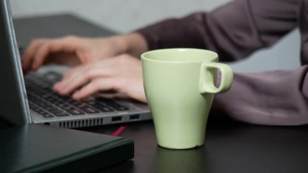 女性は、ノート パソコンにお茶を注いだ。オフィスで、4 k のクローズ アップ作品, — ストック動画