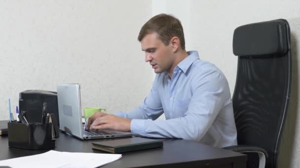 Ein junger Mann schüttete Tee auf einen Laptop. arbeitet im Büro. Zeitlupenaufnahmen, 4k — Stockvideo