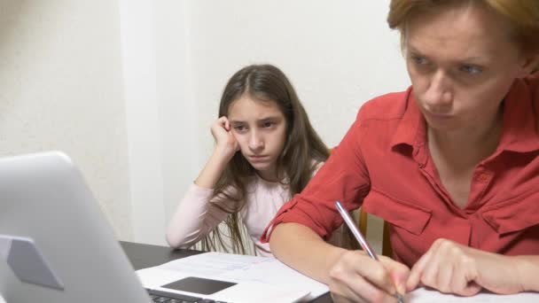 Madre e hija trabajando juntas en una tarea en un portátil. aprendizaje en línea, escuela en línea. 4k . — Vídeo de stock