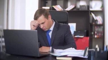 belgeler, inceden inceye gözden geçirmek bir işadamı, bir dizüstü bilgisayar kullanarak frowns, ofiste acil bir görev yapmaz, yeterli zaman değil 4k. ofis çok sıcak, Klima çalışmıyor