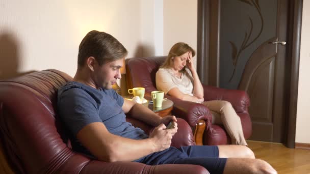 Семейный вечер, муж и жена сидят в кресле в своем доме и выясняют отношения. 4k — стоковое видео