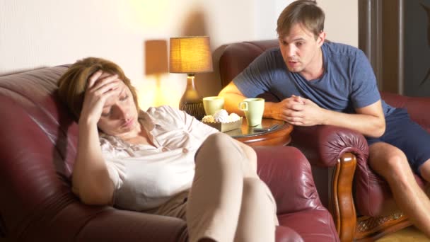 Malam keluarga, suami dan istri duduk di kursi di rumah mereka dan mencari tahu hubungan mereka. 4k — Stok Video