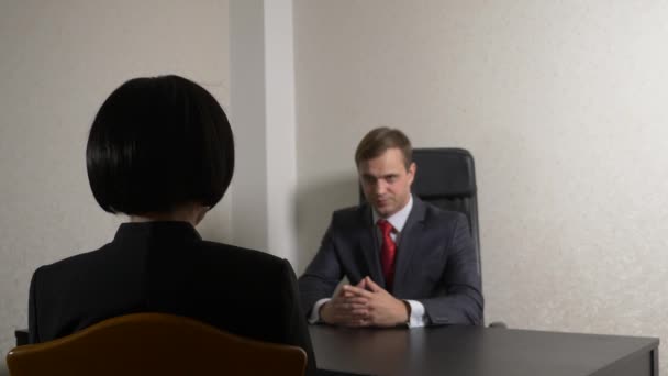 Мужчина в костюме задает вопросы брюнетке во время интервью. 4k. интервью. вербовка — стоковое видео