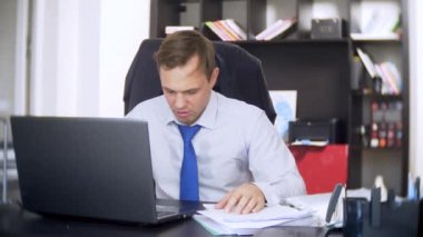 belgeler, inceden inceye gözden geçirmek bir işadamı, bir dizüstü bilgisayar kullanarak frowns, ofiste acil bir görev yapmaz, yeterli zaman değil 4k. ofis çok sıcak, Klima çalışmıyor
