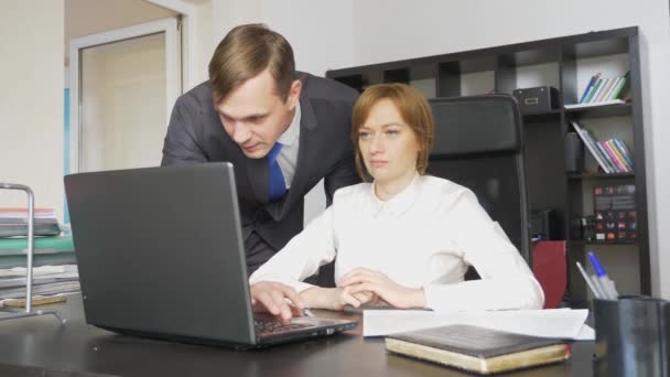 Мужчина и женщина в строгих костюмах за работой на ноутбуке, документы, обсуждение в офисе. 4k . — стоковое видео