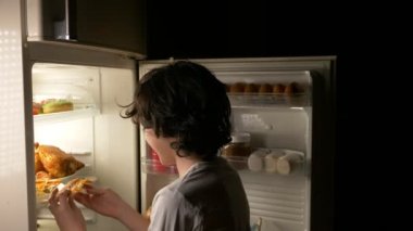Gece yarısı buzdolabının önünde yeme çocuk. 4k