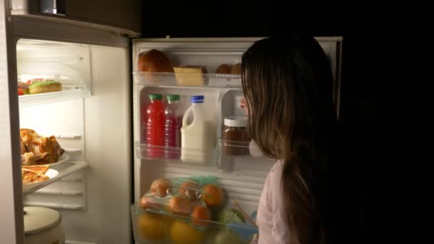 Dospívající dívka otevírá lednici v noci. Noční hlad. strava. obžerství, 4k — Stock video