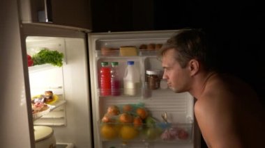 Genç bir kaslı adam geceleri buzdolabı açılır. gece açlık. diyet. oburluk, 4k