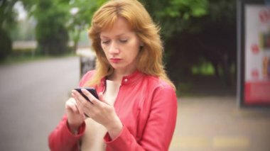 otobüs durağında duran ve bir cep telefonu kullanarak kadın. 4k