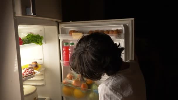 Child eating in front of the refrigerator in the middle of the night. 4k — Stock Video