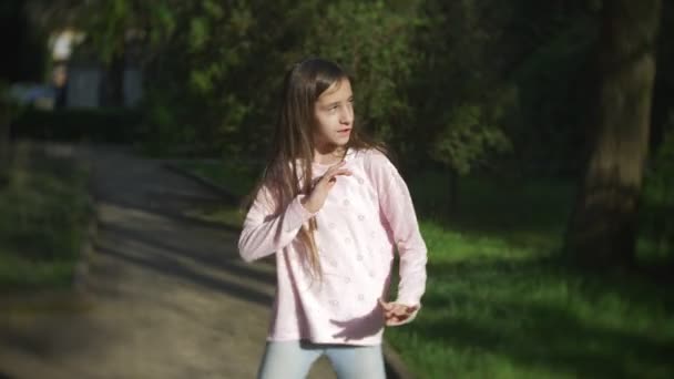 4K. menina elegante com cabelo longo dançando dança moderna em um parque da cidade . — Vídeo de Stock